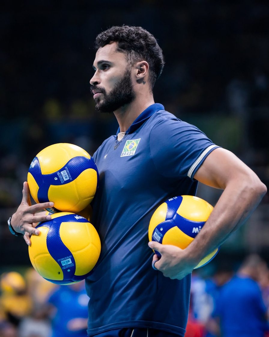 Fabinho Marques segurando bolas de vôlei em quadra